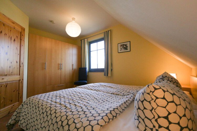 Schlafzimmer 1 mit Doppelbett unter der Dachschraegen, grossem Kleiderschrank neben dem Fenster