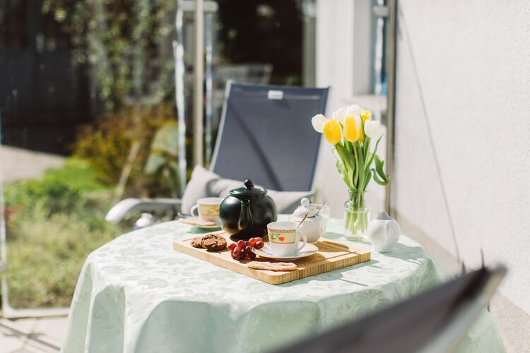 gedeckter Tisch auf der sonnigen Terrasse mit 2 Stuehlen