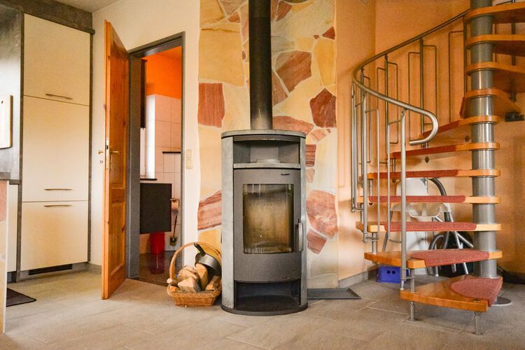Gemütliches Wohnzimmer mit Kamin im Ferienhaus Falke in Zingst, ideal für Familienurlaub an der Ostsee
