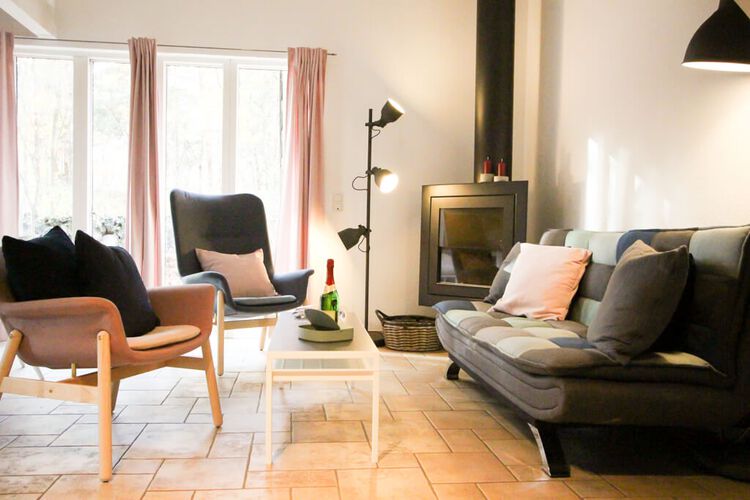 auf hellen Fliesenboden warten die Wohnzimmermoebel wie das Sofa , die gemuetlichen Sessel auf Sie, der Kamin in der Ecke wertet das gesamte Wohngefuehl auf , die grossen Fenster mit dem Zugang zur Terrasse spenden genuegend Licht