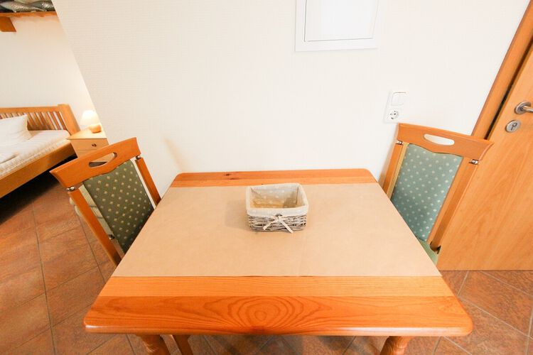 gefliester Essbereich mit Esstisch und 2 Stuehlen neben der Eingangstuer